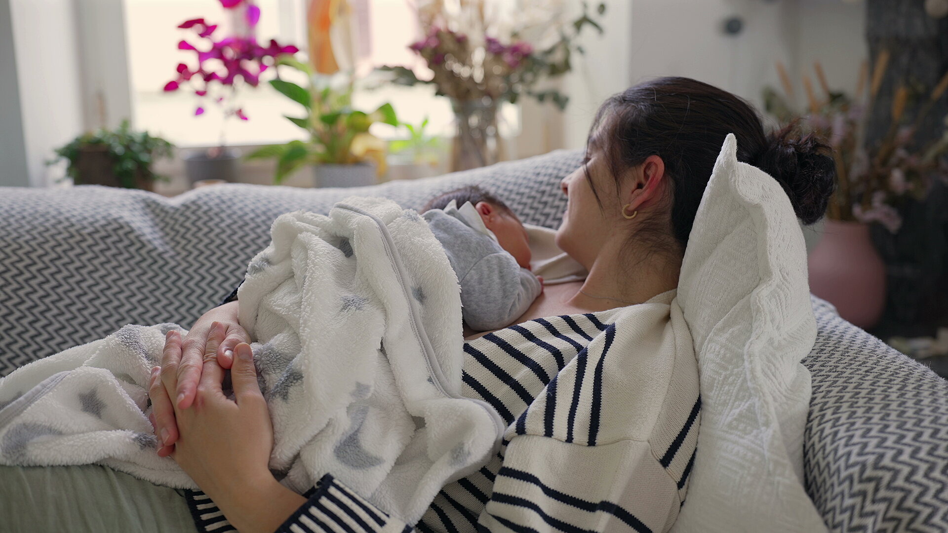 Mutter liegt mit Neugeborenem auf dem Sofa