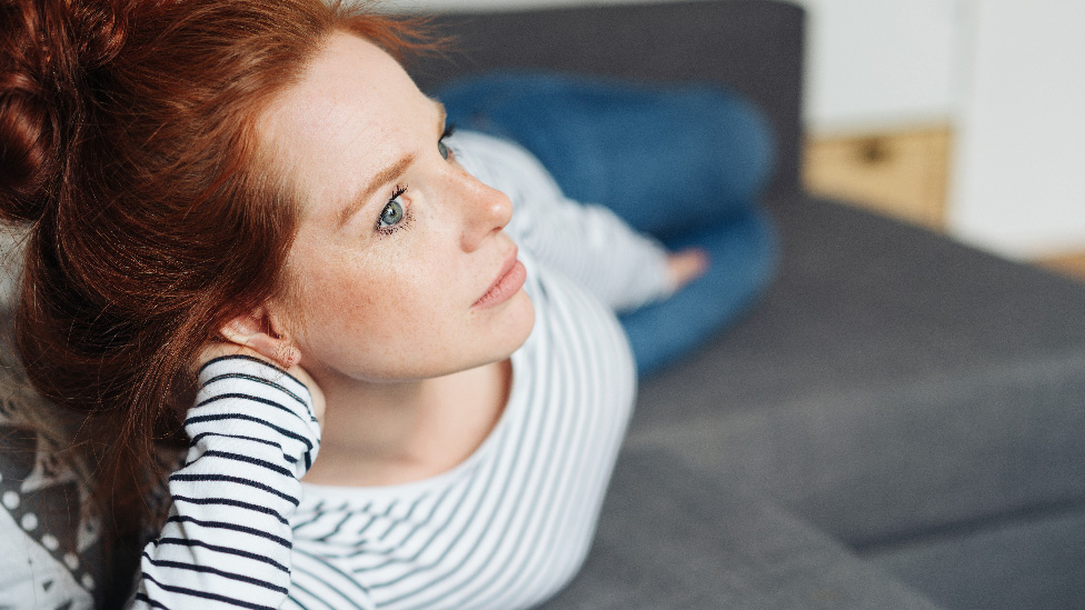 Die Frau im Schwangerschaftskonflikt: Will ich das Kind? (Quelle: contrastwerkstatt - stock.adobe.com) Frau liegt auf dem Sofa und schaut nachdenklich in die Ferne