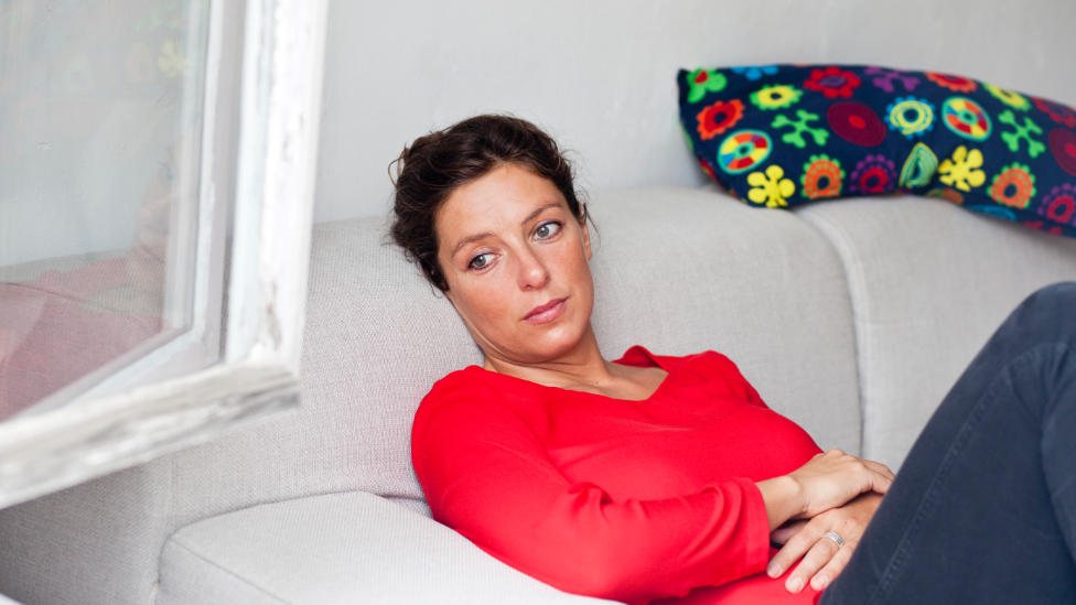 Fruchtbarkeitsstörungen bei der Frau (Quelle: BZgA/HN/Eichhöfer) Nachdenkliche Frau sitzt auf Sofa