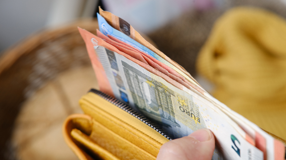Hand hält Geldbeutel in dem mehrere Euro-Scheine stecken
