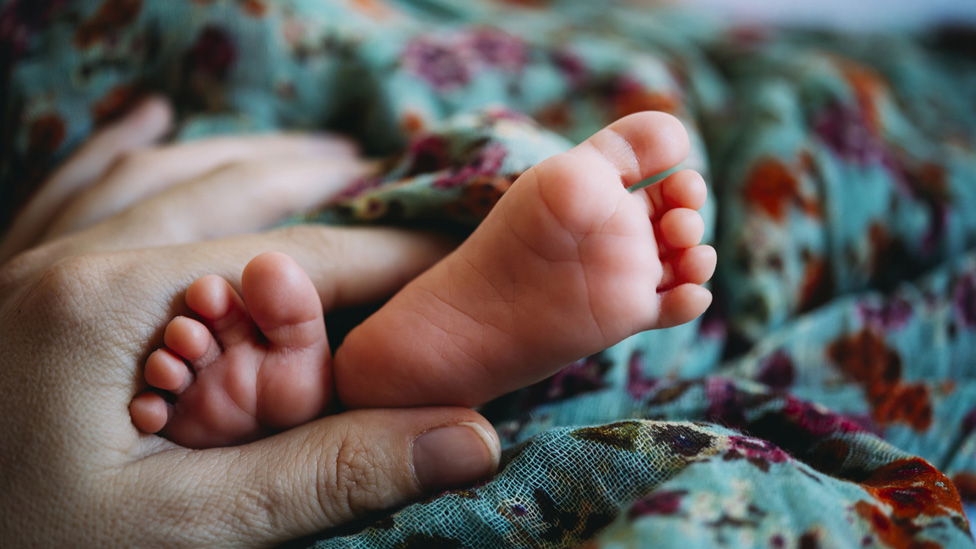 Alleingeburt (Quelle: DEEPOL by plainpicture/Gemma Ferrando) Hand hält Füße eines Babys