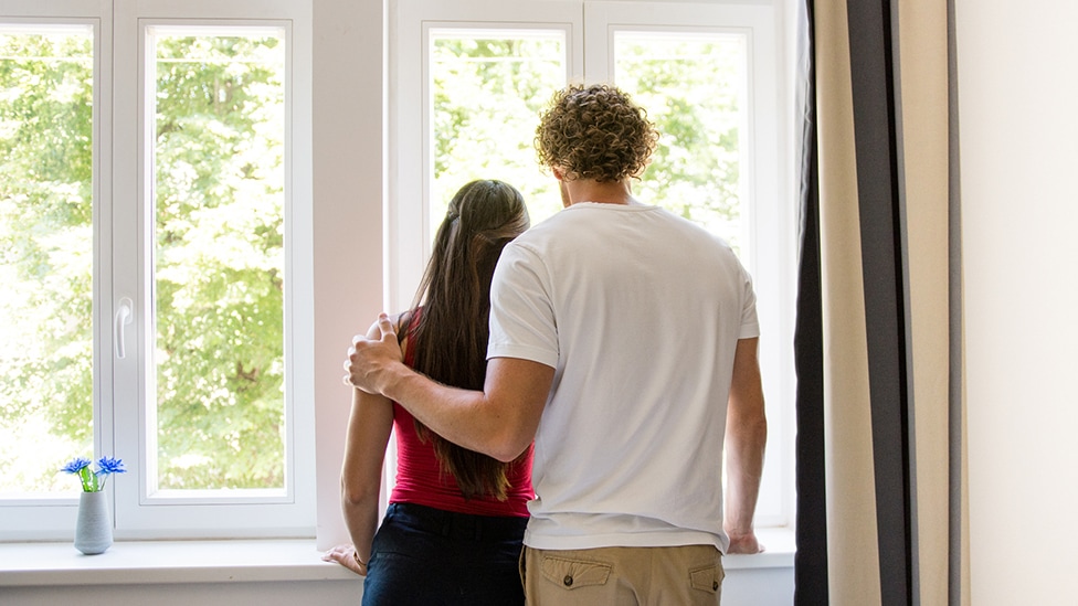 Schwangerschaftsabbruch nach auffälligem Befund (Quelle: kovaciclea / E+ / via Getty Images) Partner legt seiner Partnerin die Hand auf die Schulter und beide schauen aus dem Fenster